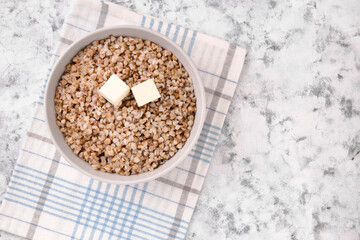 Freshly cooked buckwheat porridge in a plate on a gray background.