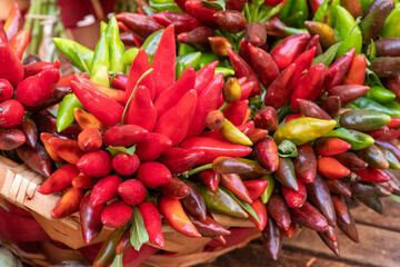 Bunches of red and green hot chili peppers in a basket in a street food market, close up