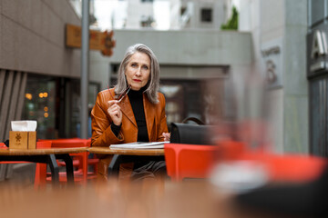 Grey white senior woman reading book while sitting in cafe