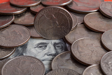 Benjamin Franklin's face from a 100 American dollar bill surrounded by 25 cents