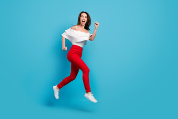 Fototapeta na wymiar Photo of shiny excited young lady wear off-shoulders shirt jumping high running empty space smiling isolated blue color background