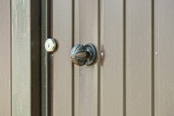 one round black iron door handle on brown metal door outside