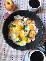 fried eggs with ham and herbs in a frying pan.