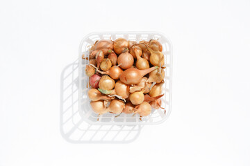 Small bulbs for growing green onions. Brown bulbs in the husk are lying in a plastic container on a white background