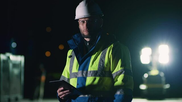 Male contractor with tablet at night