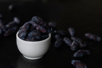 Blue Honeysuckle berries in a white porcelain bowl on a dark background