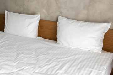 Two white pillows are on a wide empty bed