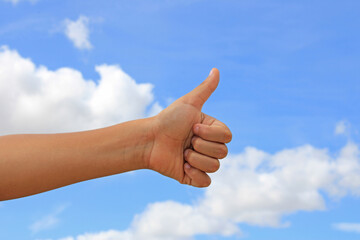 Hand with thumb up with blue sky in the background