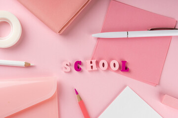 Pink school supplies and word school on pink background. Back to school concept. Top view