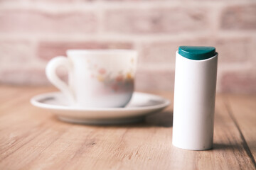 artificial sweetener container and tea cup on table 