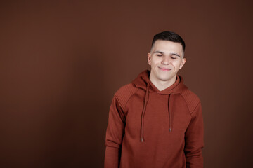 Portrait of a young guy showing his hands to the side on a brown background. Profitable proposition.