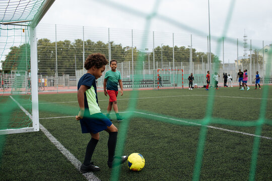 Little Boy Playing Football. African American Schoolboy At Stadium. Young Kids Running Outside. Happy Black Children Practicing Soccer. Training At Field With Ball. Exercise And Healthy Lifestyle