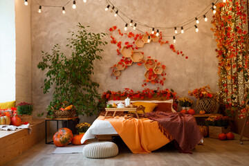 Autumn bedroom, living room interior. Red and yellow leaves and flowers in the vase and pumpkin on...