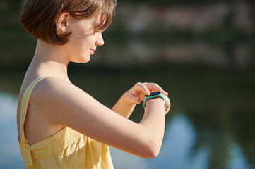 A teenage girl sets up a fitness tracker. Walking tour.