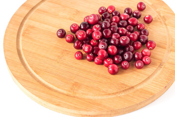 A useful marsh forest ripe berry cranberry lies on a kitchen wooden board. Isolated on a white background. 