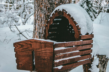 A baby cot abandoned in the winter forest. Wooden snow-covered cradle.