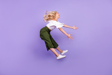 Full length body size girl jumping up laughing flying on wind isolated pastel purple color...
