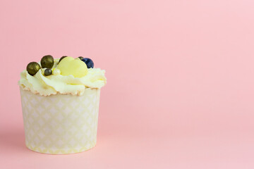 Beautiful lemon cupcake with a decoration from berries on a pink background