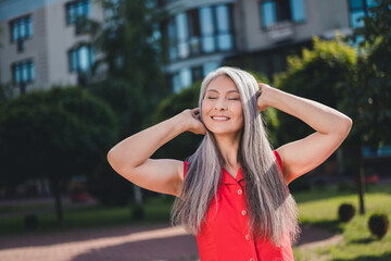 Portrait of attractive dreamy cheerful grey-haired woman enjoying sunny weather spending free time weekend outdoors