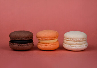 Orange, brown, white macarons in a row on a brown background stock images. Delicious french macarons isolated on a brown background with copy space for text