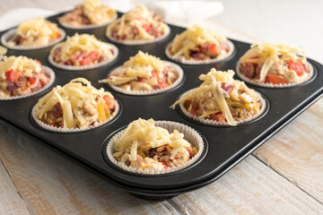 Prepared pizza muffins from yeast dough with tomatoes, vegetables and cheese in a baking tray ready...