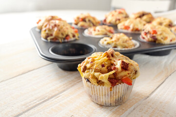 Tasty baked pizza muffins as finger food for a party from yeast dough, tomatoes, vegetables, sausage and cheese on a wooden table, copy space, selected focus - obrazy, fototapety, plakaty