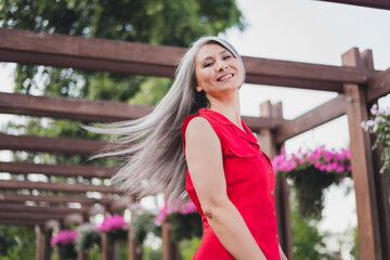Portrait of attractive careless cheerful grey-haired woman spending day free time throwing hair on...