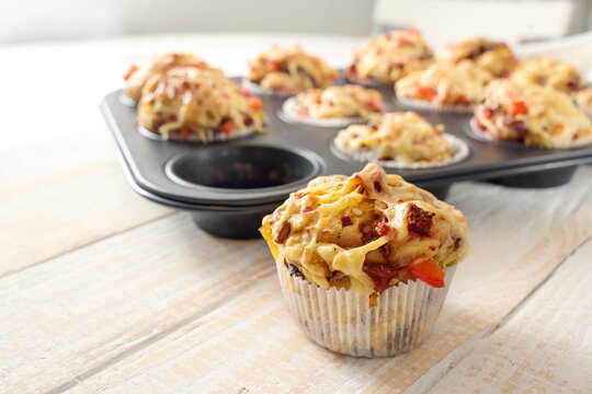 Tasty baked pizza muffins as finger food for a party from yeast dough, tomatoes, vegetables, sausage and cheese on a wooden table, copy space, selected focus