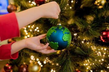 Close-up of little girl hanging Xmas glass bauble decoration ornament globe planet earth on...