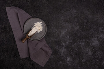 Wheat flour in a concrete plate on a dark background. The ingredient. Bakery products.