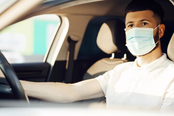 Fototapeta na wymiar man in a protective medical mask driving a car, the concept of preventing the spread of an epidemic