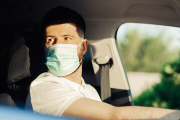 Fototapeta na wymiar man in a protective medical mask driving a car, the concept of preventing the spread of an epidemic