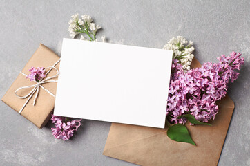 Obraz na płótnie Canvas Greeting or invitation card mockup with gift box, envelope and spring lilac flowers