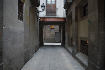 Narrow Street with old buildings leading to a bright area in Barcelona, Spain