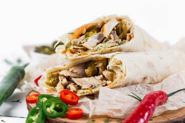 Shawarma with chicken, with sauce, onions, pickles, herbs and hot red pepper on a light background