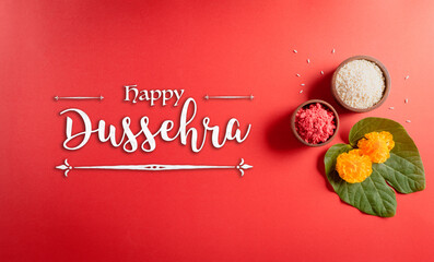 Happy Dussehra. Yellow flowers, green leaf and rice on red background. Dussehra Indian Festival concept.
