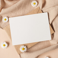Blank clipping path paper sheet card with mockup copy space, chamomile flower buds and muslin cloth on neutral beige background. Minimal aesthetic business brand template. Flat lay, top view - obrazy, fototapety, plakaty