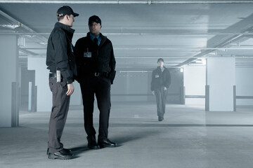 Fototapeta premium Security guards talking in empty parking garage