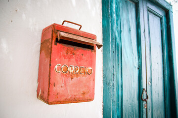 boite aux lettres rouge sur un mur blanc avec vieille porte bois bleue