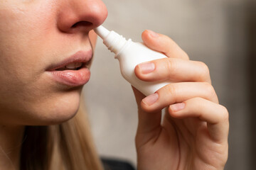 The girl treats nasal congestion. close-up. nasal spray.