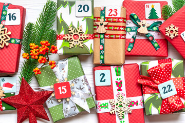 Handmade wrapped red, green gift boxes decorated with ribbons, snowflakes and numbers, Christmas...
