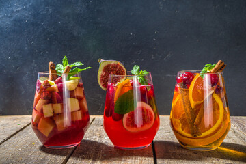 Traditional autumn winter drink hot spicy sangria - red, pink, white. With cider, pink red wine, apples, oranges, pomegranate, cranberry, plum, figs, cinnamon sticks. Wooden rustic table copy space