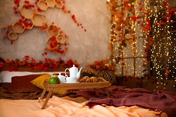 Autumn bedroom, living room interior. Wooden tray with breakfast on bed with fall background.