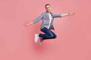 Full size profile side photo of young guy happy positive smile jumping have fun open hands isolated on pink color background