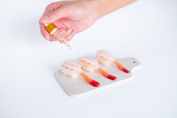 Raw Shrimp prawn sushi in japanese restaurant. Sushi - ama Ebi Nigiri on white board on white background. Cook drips the sauce. High quality photo 
