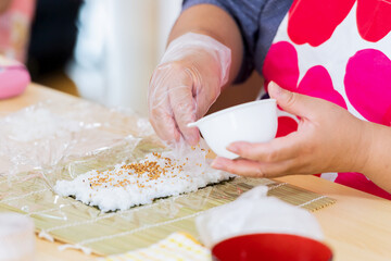 Obraz na płótnie Canvas 料理教室で巻き寿司を作る女性の手元