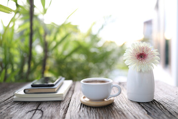 White coffee cup and notebook with gerbera flower