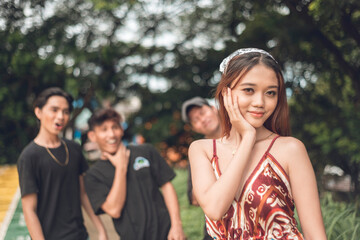 A beautiful young lady pleased that she is admired by three stunned men in the back complimenting...