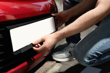 Man installing vehicle registration plate outdoors, closeup