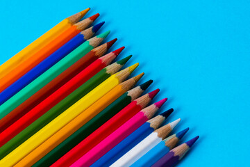 Set of wooden colored pencils on a blue sheet of paper background